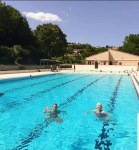 two people are swimming in a swimming pool at Rue Basse - village house overlooking the Pyrenees in Montréal