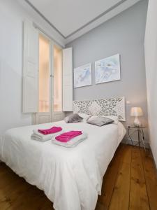 a white bedroom with a large white bed with towels on it at AsAtHome Arenal Apartment in Madrid