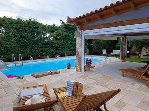 een patio met stoelen en een zwembad bij Celestial Azure Villa, your Athenian Country House Retreat in Markopoulon