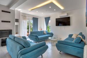 ein Wohnzimmer mit blauen Sofas und einem TV in der Unterkunft Villa Tami in Hreljići