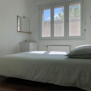 a bedroom with a large white bed with two windows at Le 21 in Écuires