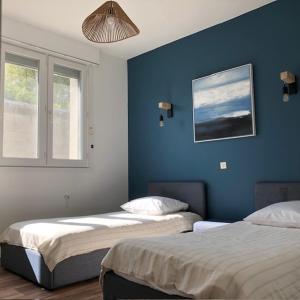 two beds in a room with blue walls and a window at Le 21 in Écuires