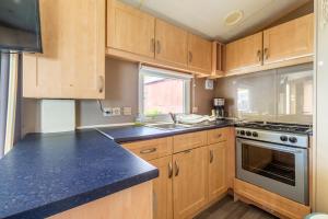a kitchen with wooden cabinets and a stove top oven at Mobil Home Le Berlin in Noyelles-sur-Mer