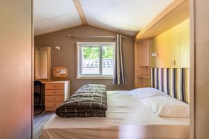 niewielka sypialnia z łóżkiem i oknem w obiekcie Mobil Home Le Berlin w mieście Noyelles-sur-Mer