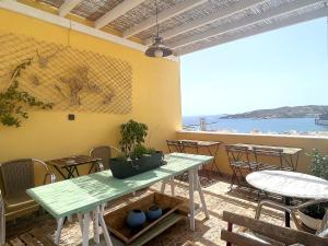 a patio with tables and chairs with a view of the ocean at Pefkakia Park in Ermoupoli