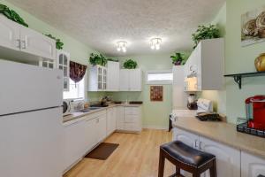 a kitchen with white cabinets and green walls at Muskegon Getaway with Fire Pit, Patio Less Than 1 Mi to Lake in Muskegon