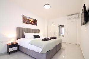 a white bedroom with a large bed and a tv at סוויטה אגריפס 8 in Jerusalem