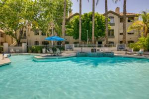 een zwembad met een parasol en een gebouw bij Energizing Scottsdale Vacation Rental! in Scottsdale