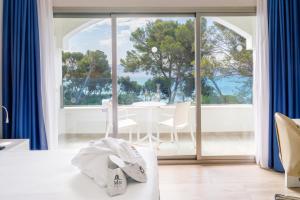 a room with a large window and a table with chairs at Mar Hotels Alcanada in Port d'Alcudia