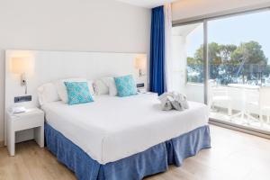 a bedroom with a large bed and a large window at Mar Hotels Alcanada in Port d'Alcudia