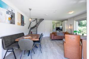 ein Wohnzimmer mit einem Tisch, Stühlen und einer Treppe in der Unterkunft The island life texel met jacuzzi in De Koog