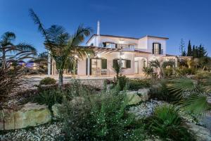ein großes weißes Haus mit Palmen und Pflanzen in der Unterkunft VILLA CARACOL Heated Swim Spa & Mini-Golf in Luz de Tavira