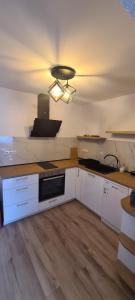 une cuisine avec des armoires blanches et un appareil noir dans l'établissement къща за гости Сънрайс Чепеларе, à Chepelare