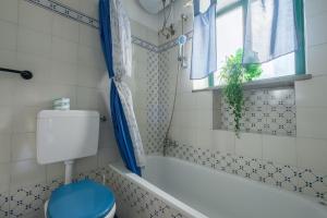 ein Bad mit einem WC, einer Badewanne und einem Fenster in der Unterkunft Angela Appartament in Lipari