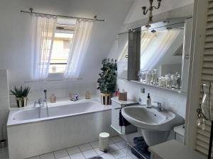 a white bathroom with a tub and a sink at Maison Beaumont in Springe