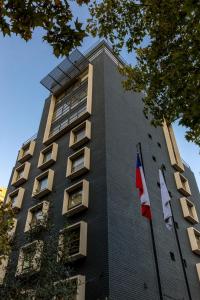 un edificio alto con dos banderas delante en Rugendas by Time, en Santiago