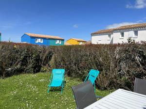 two blue chairs and a table in the grass at 52amareyeurs in Le Château-dʼOléron