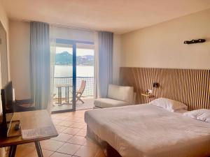 a hotel room with a bed and a view of the ocean at Hôtel Castel d'Orcino in Calcatoggio