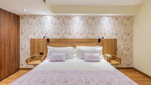 um quarto com uma cama grande e papel de parede floral cor-de-rosa em Rugendas Hotel Boutique by Time Hotel & Apartments em Santiago