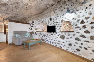 un soggiorno con parete in pietra, divano e tavolo di Cueva El Desvelo a Tijarafe
