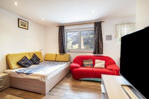 a living room with a red bed and a couch at Haus Reimon Apt Monika in San Leonardo in Passiria
