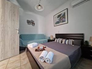 een slaapkamer met een bed met handdoeken en een bank bij Afroditi's 2 in Eresos