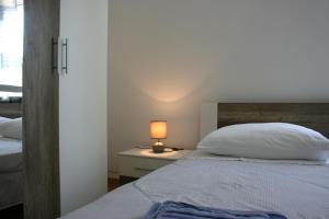 a bedroom with a bed and a lamp on a table at Apartments Antea in Trogir