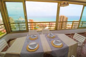 une table avec des chapeaux et des chaises dans une pièce avec des fenêtres dans l'établissement 1 min a pie Playa San Juan - Increíbles vistas al mar - 4 habs - Gran terraza - Urbanización con piscina padel y tenis, à Alicante