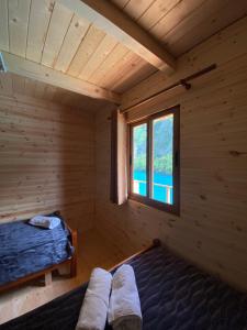 Cabaña de madera con cama y ventana en Riverside Komani Lake en Koman