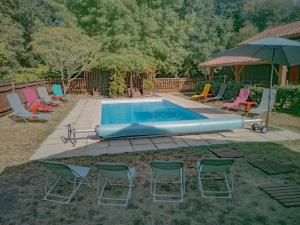 einen Pool mit Stühlen und einem Sonnenschirm in der Unterkunft Gite de pernaout in Bélis