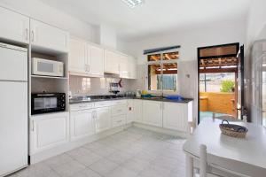 Una cocina blanca con gabinetes blancos y una mesa. en Cantinho Solpraia, en Porto Santo