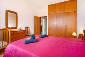 1 dormitorio con 1 cama rosa y 2 toallas azules en Cantinho Solpraia, en Porto Santo