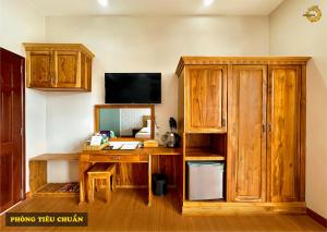 a room with a wooden desk and a tv at Rồng Vàng Resort in Tri Tôn