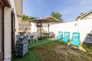 eine Terrasse mit Stühlen, einem Tisch und einem Sonnenschirm in der Unterkunft Villa Terre Océan Côte Atlantique 4 in Soulac-sur-Mer