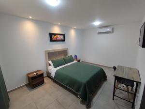 Un dormitorio con una cama verde y una mesa en Hotel Villa Bosco, en Palmira