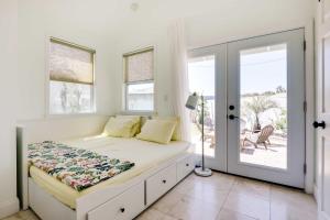 a white bedroom with a bed and windows at Chic Coastal Cottage with Fire Pit Walk to Pier! in Saint Augustine Beach
