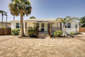 a house with palm trees in front of it at Chic Coastal Cottage with Fire Pit Walk to Pier! in Saint Augustine Beach