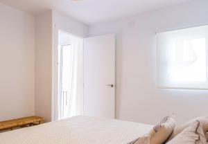 ein weißes Schlafzimmer mit einem Bett und einem Fenster in der Unterkunft Alonis Suites Old Town - Trinitat 2 in Villajoyosa