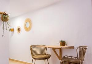 einen Tisch und Stühle in einem Zimmer mit einer weißen Wand in der Unterkunft Alonis Suites Old Town - Trinitat 2 in Villajoyosa