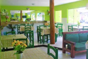 un restaurante con paredes verdes, mesas y sillas en Hotel Kalifornia, en Porto Seguro