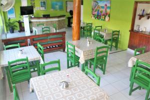 an empty restaurant with green tables and chairs at Hotel Kalifornia in Porto Seguro
