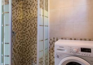 y baño con azulejos y lavadora y secadora. en Alonis Suites Old Town Penthouse, en Villajoyosa