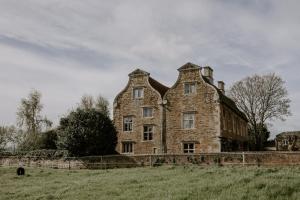 ein altes Steingebäude auf einem Grasfeld in der Unterkunft Allington Manor in Allington