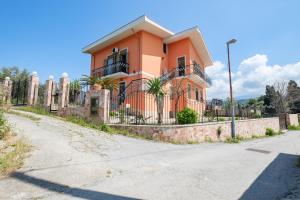 une maison orange avec une clôture devant elle dans l'établissement Casa Stella vista Eolie, à San Pier Niceto