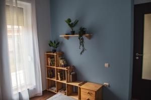 a room with a blue wall with wooden shelves at Butik Apartmanház in Fonyód
