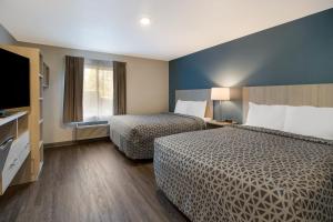 a hotel room with two beds and a flat screen tv at WoodSpring Suites Wixom - Novi in Wixom
