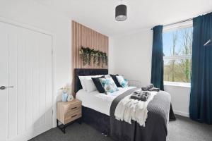 a bedroom with a large bed with blue curtains at The Scandi Gem of Nottingham - Sleeps 10 in Nottingham