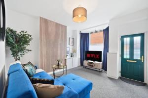 a living room with a blue couch and a tv at The Scandi Gem of Nottingham - Sleeps 10 in Nottingham