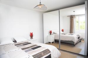 Habitación blanca con 2 camas y espejo. en Exceptionnel Loft de 250 m2, en Deuil-la-Barre