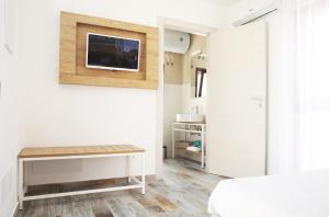 Schlafzimmer mit einem Schreibtisch und einem TV an der Wand in der Unterkunft Gli Archi garden rooms in Favignana
